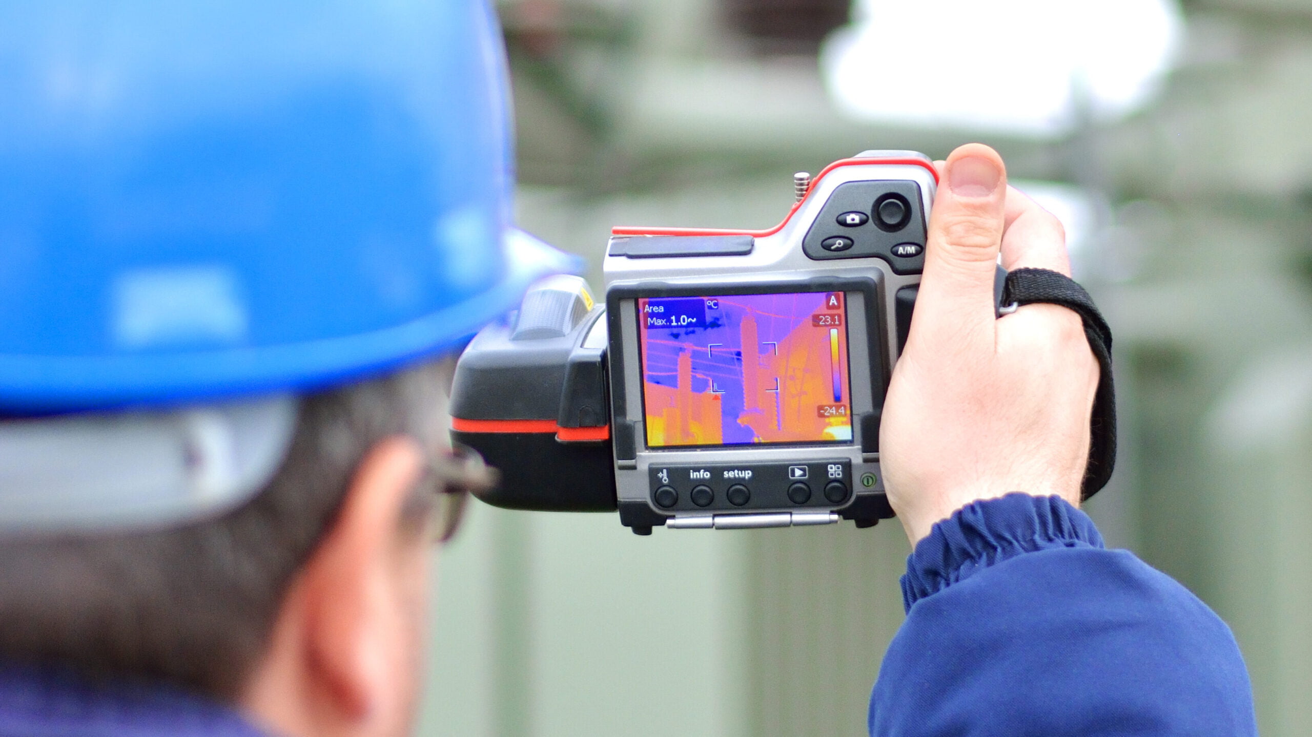 A thermal imaging camera held by a man conducting an energy assessment.